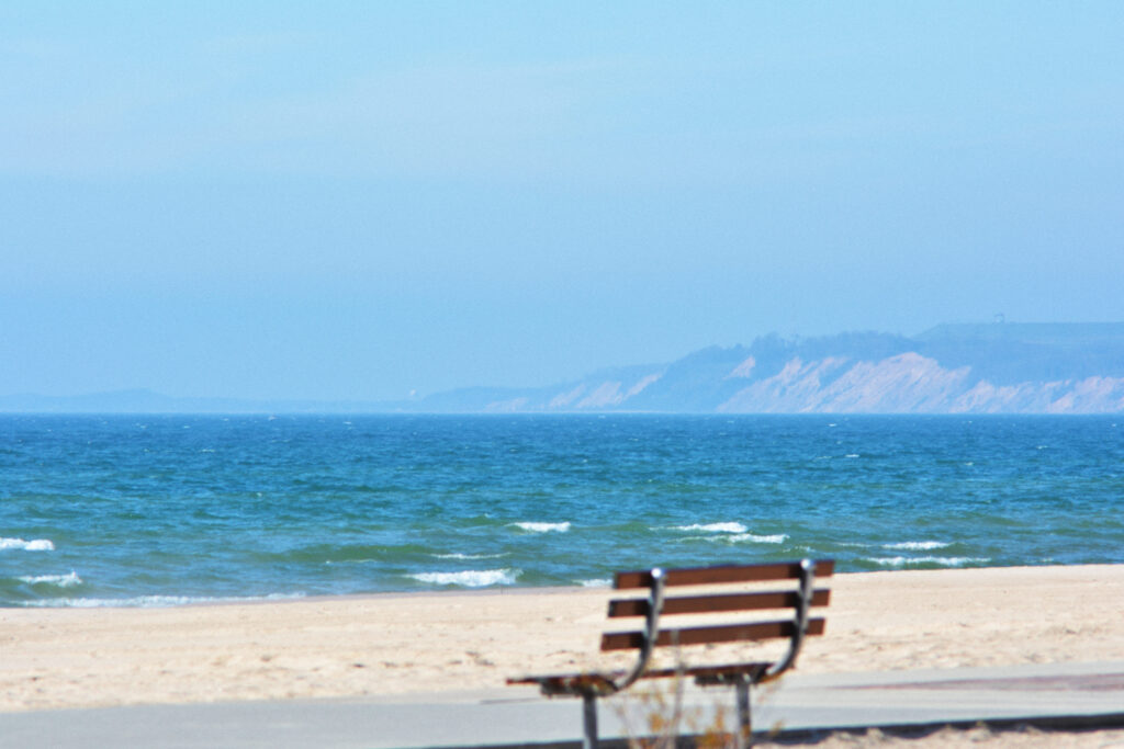 Wooden bench on a northern Michigan beach overlooking the lake and a distant shore.