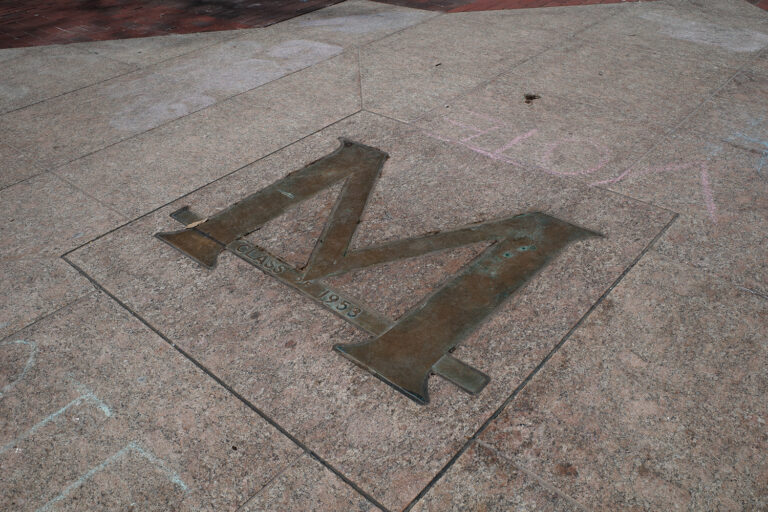 Bronze block letter M at the center of the University of Michigan Diag.