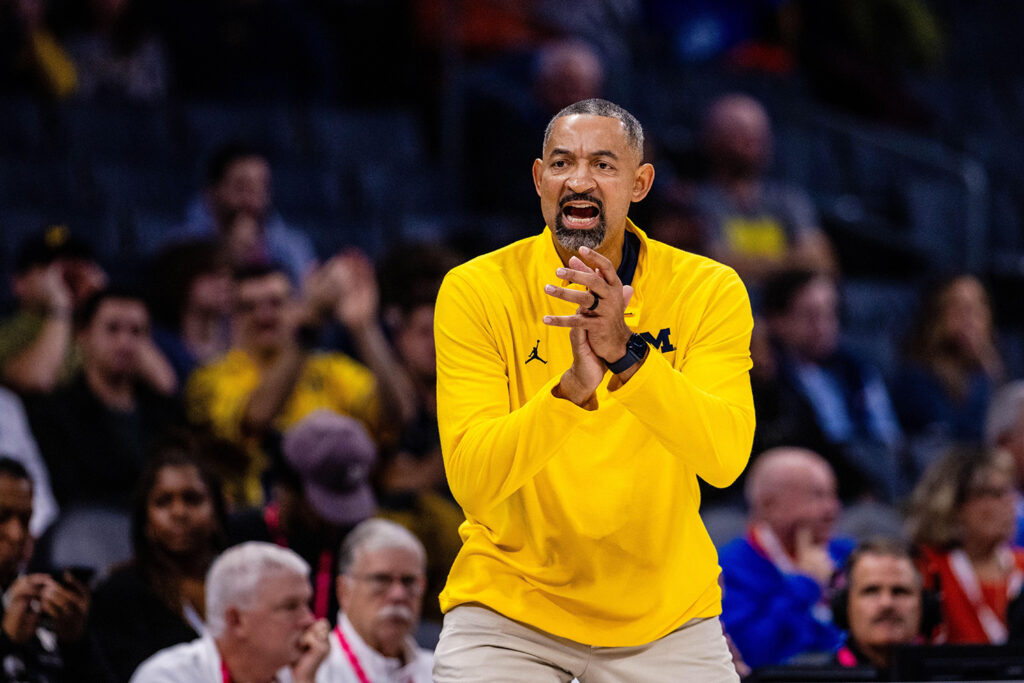 Photo of former Michigan Basketball coach Juwan Howard clapping court side during a game.