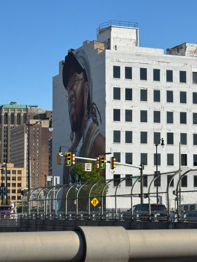 View of bridge and Mural with African American man on large building in downtown Detroit.