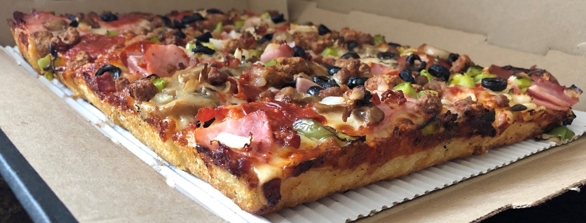 Detroit style pizza in cardboard pizza box.