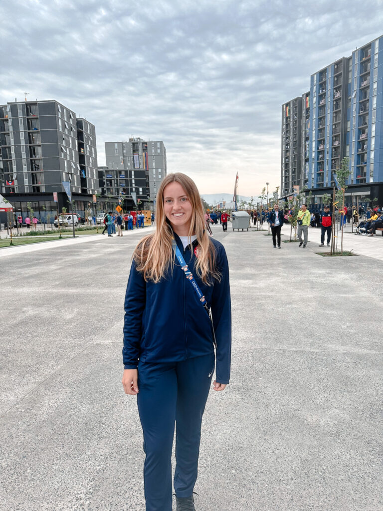 Abby Tamer standing on walkway smiling with buildings in background.