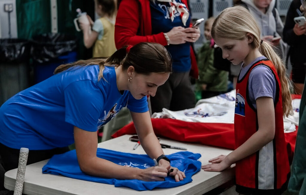 Abby Tamer signing autograph for young girl.