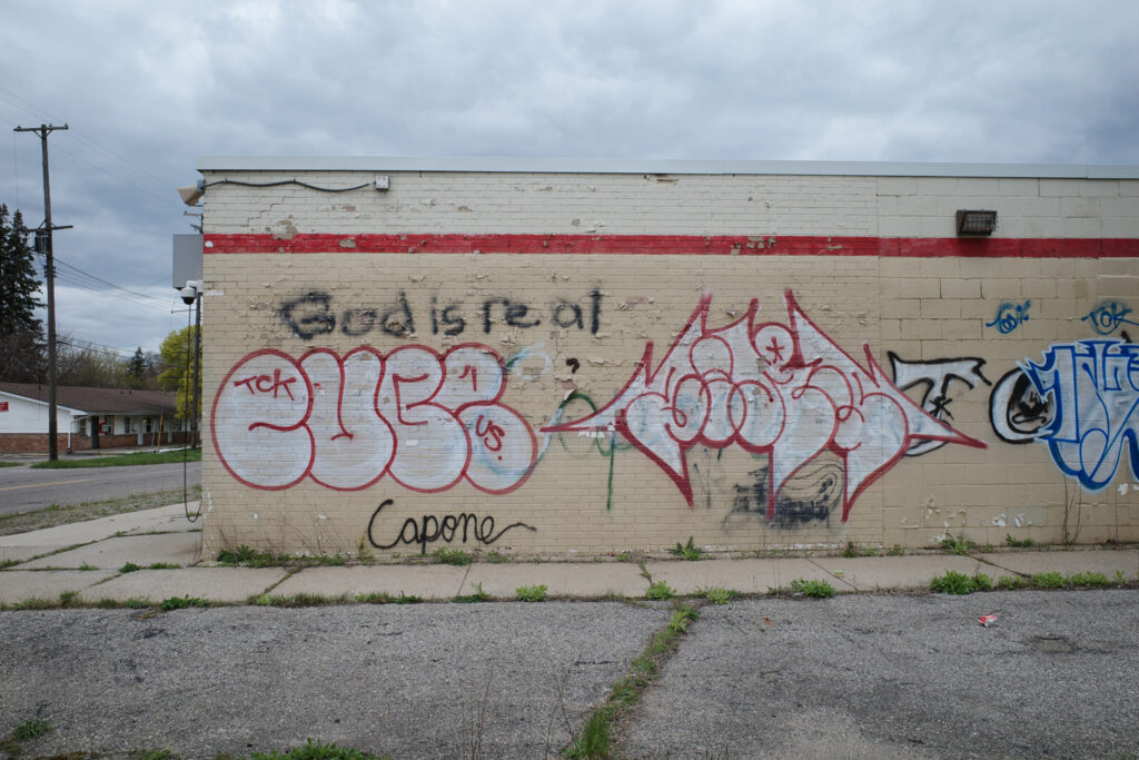 Graffiti on the side of a building reading, “God is Real.”
