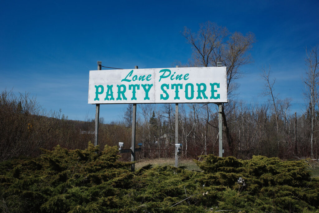 Sign for Lone Pine Party Store, white sign with green text.