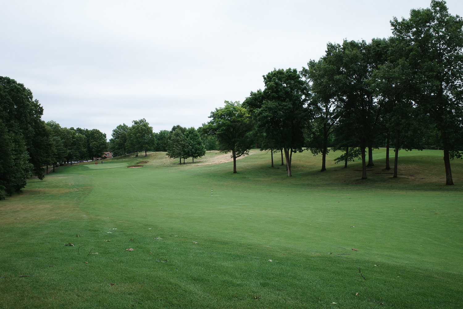 View of golf course with men in distance on green.