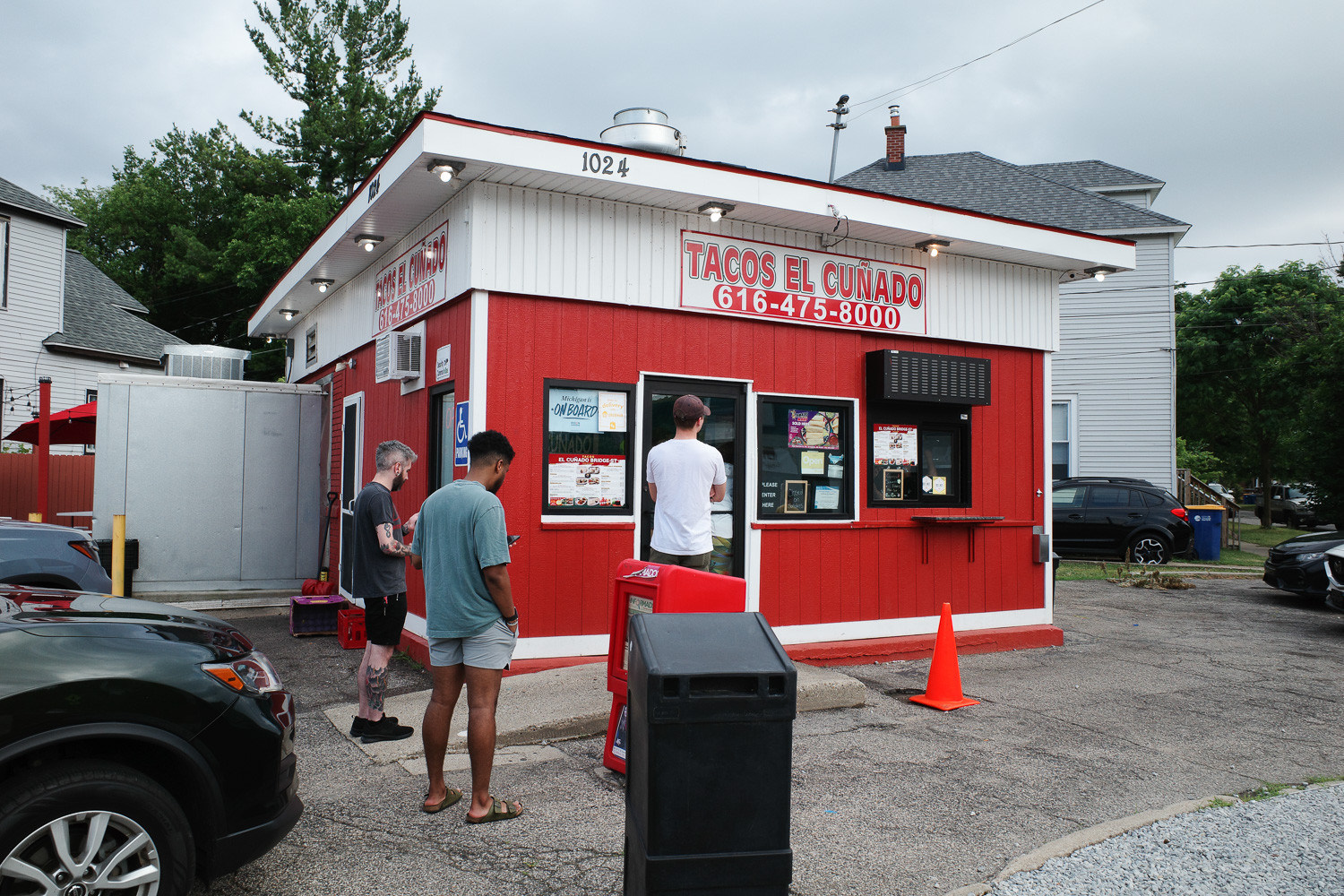 Outside of Tacos el Cunado taco stand in Grand Rapids with a crowd of people waiting.