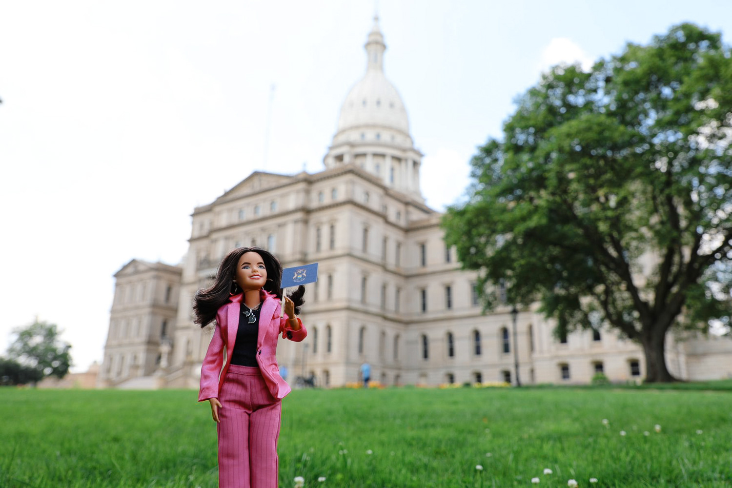 Barbie doll dressed as Gretchen Whitmer in front of Michigan state capitol building.