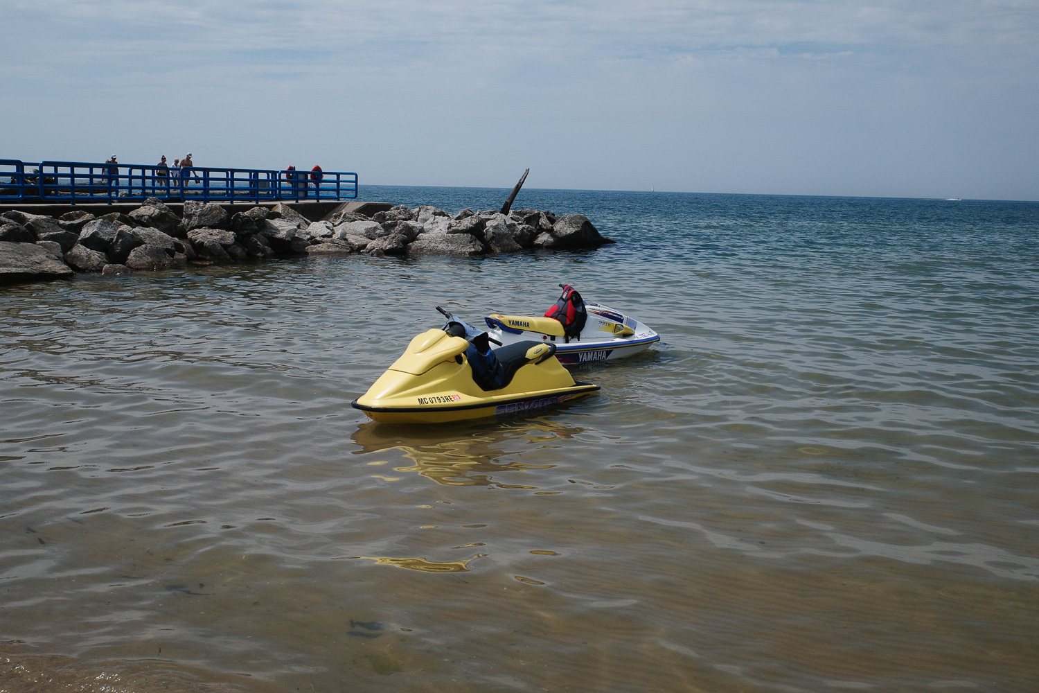 Two jet skis floating in the shoreline.