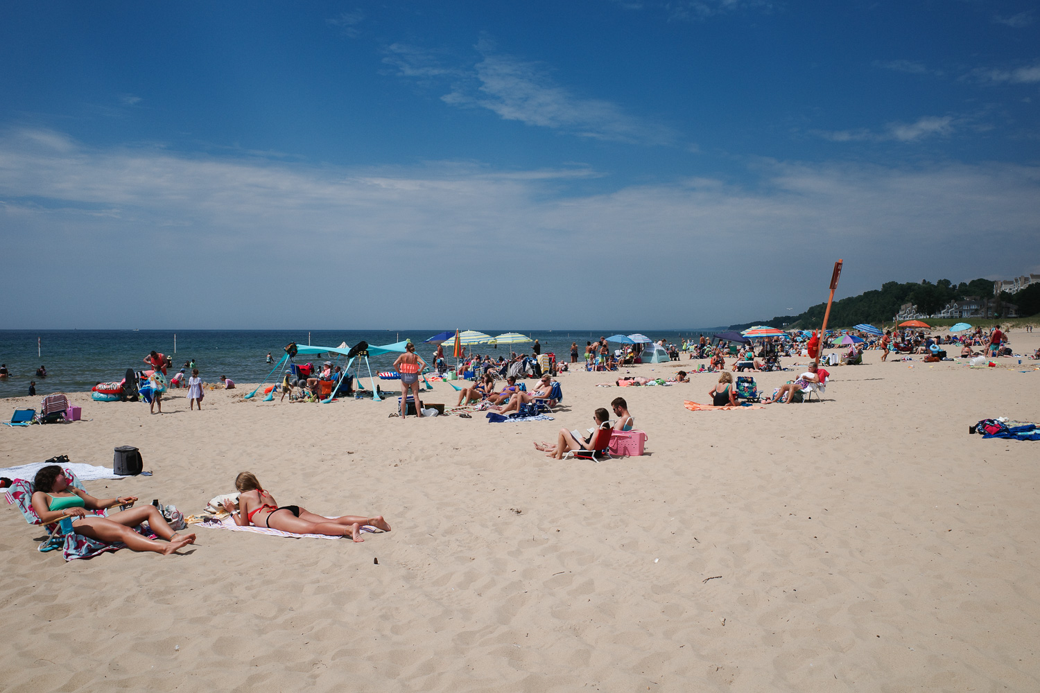 People on michigan beach with colored umbrellas.