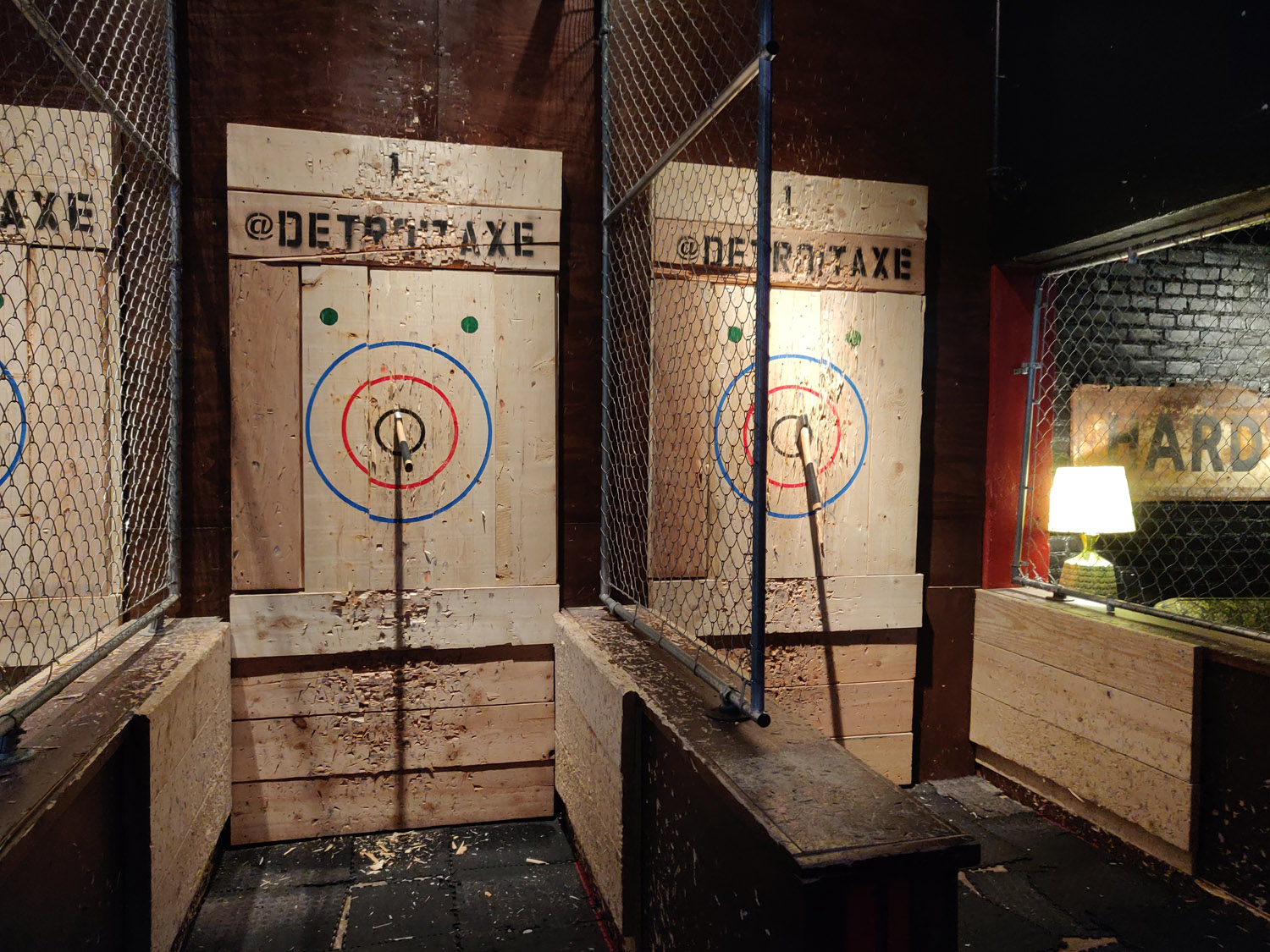 Indoor axe throwing area with signs saying “@detroitaxe”.