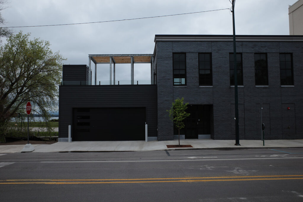 Black and gray minimalist building with lake in background.
