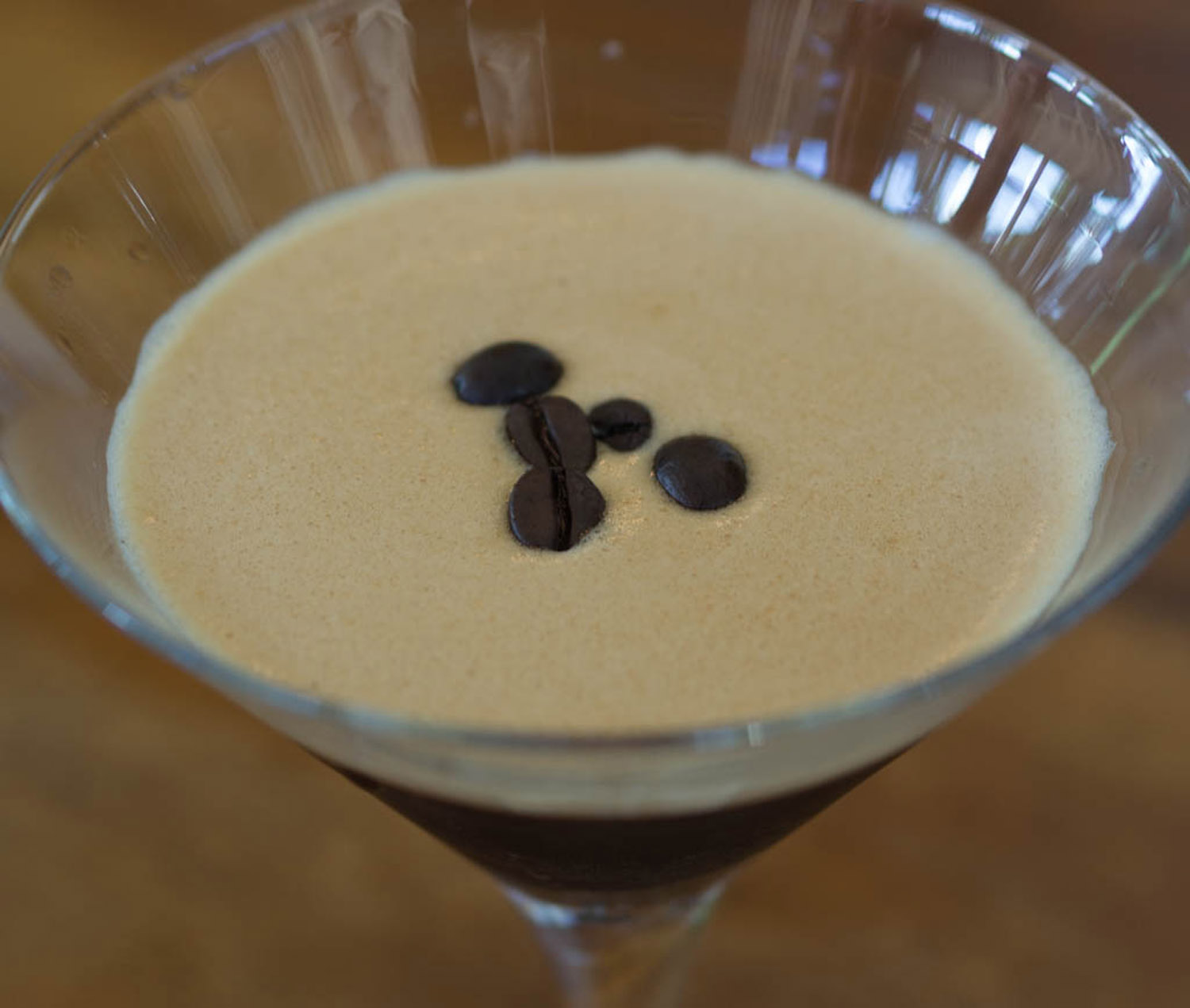 Photo of espresso martini with coffee beans on foam.