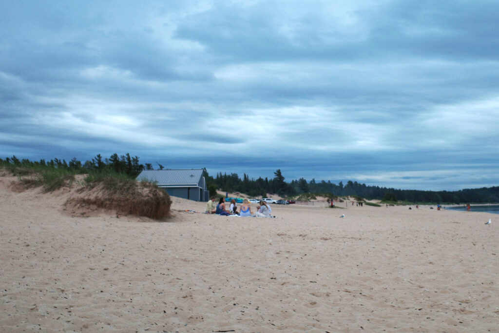 Gray stormy beach with a group huddled on blankets.