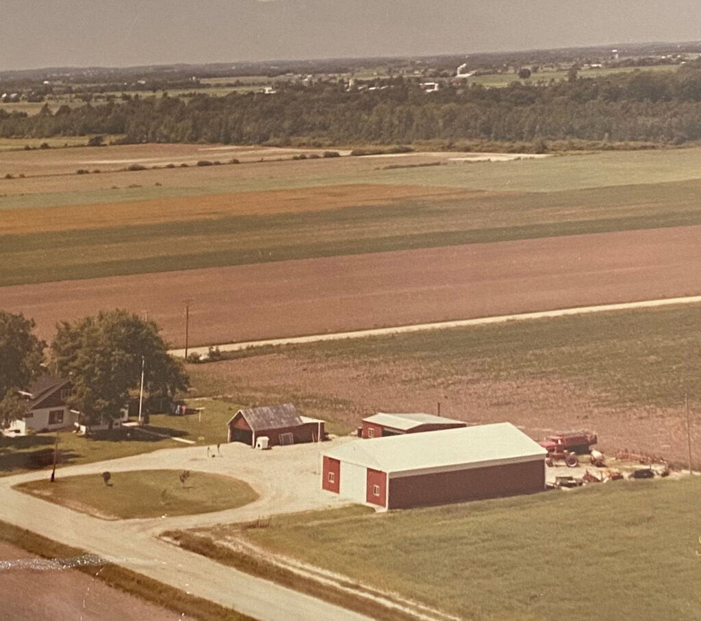 Old aerial film photograph of a red barnhouse on a Michigan farm.