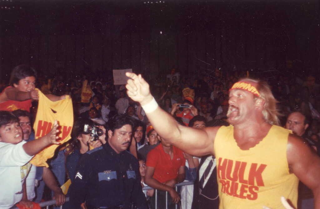 Hulk Hogan pointing into a crowd wearing yellow shirt that says "Hulk Rules"