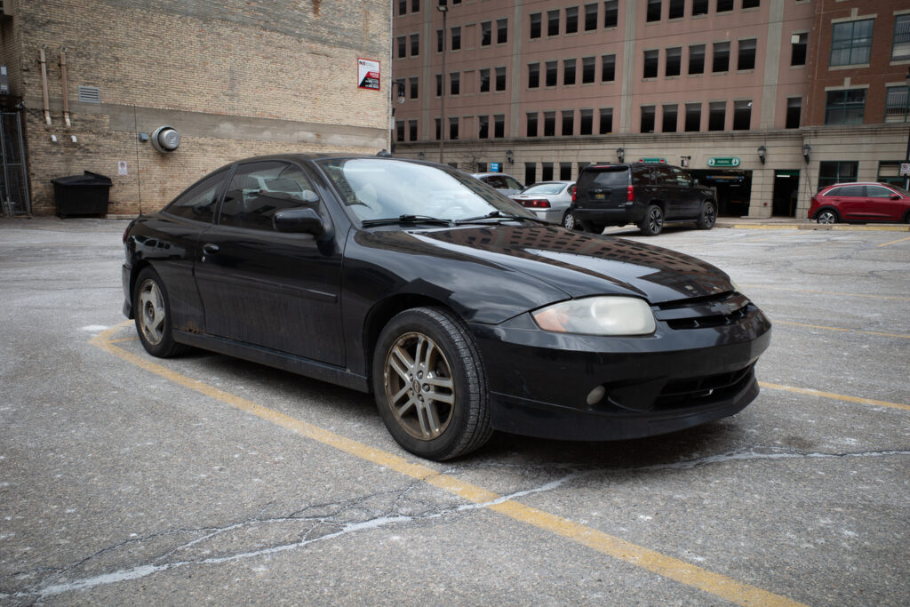 A black Chevy Cavalier in parking lot.