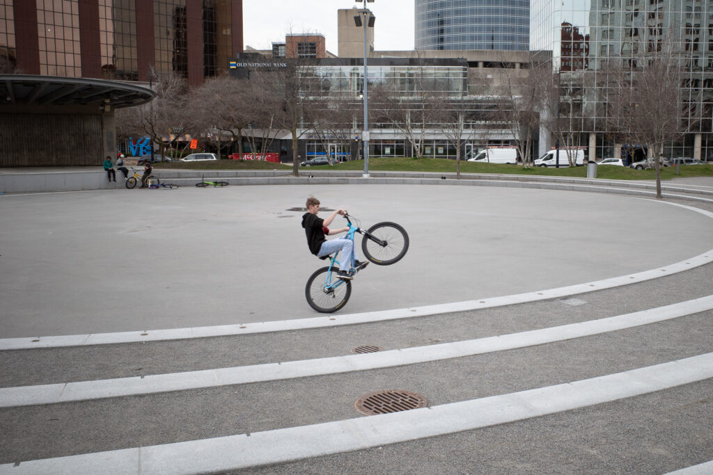 Young man popping wheelie on BMX bike in downtown Grand Rapids.