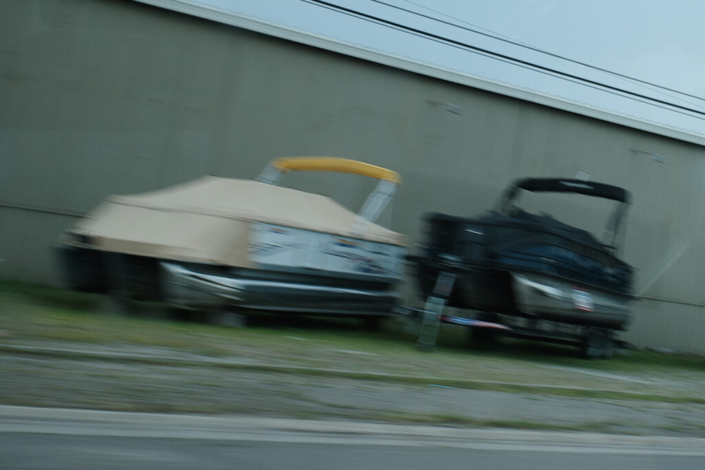 Pontoon boats on side of the road in motion blur.