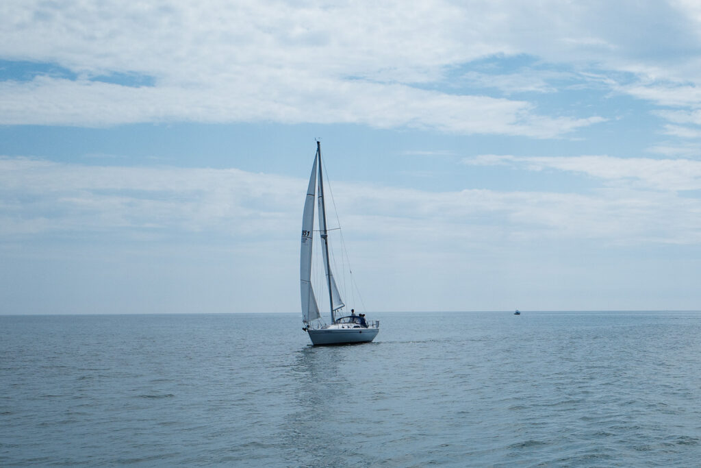 Sailboat on water with horizon in background.