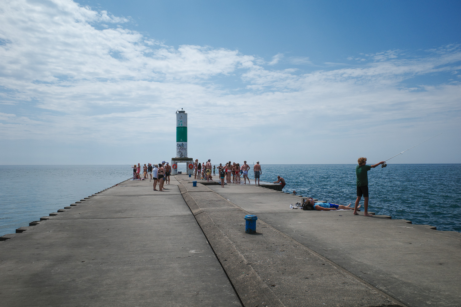 Swimmers and fishers gathering on large pier.