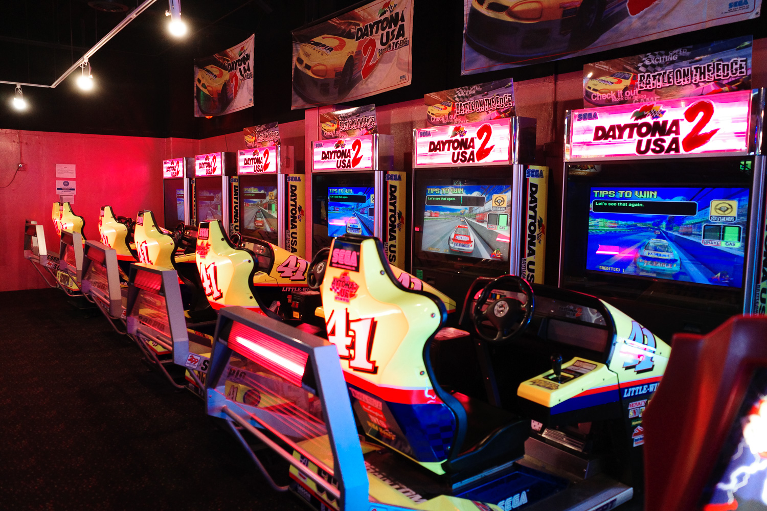 Row of Daytona USA 2 racing games in arcade.