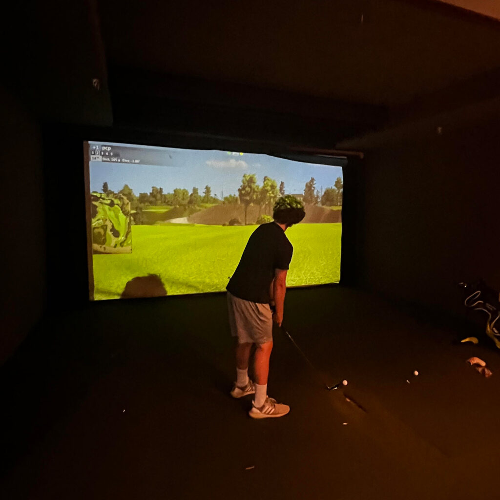 Man playing in golf simulator.