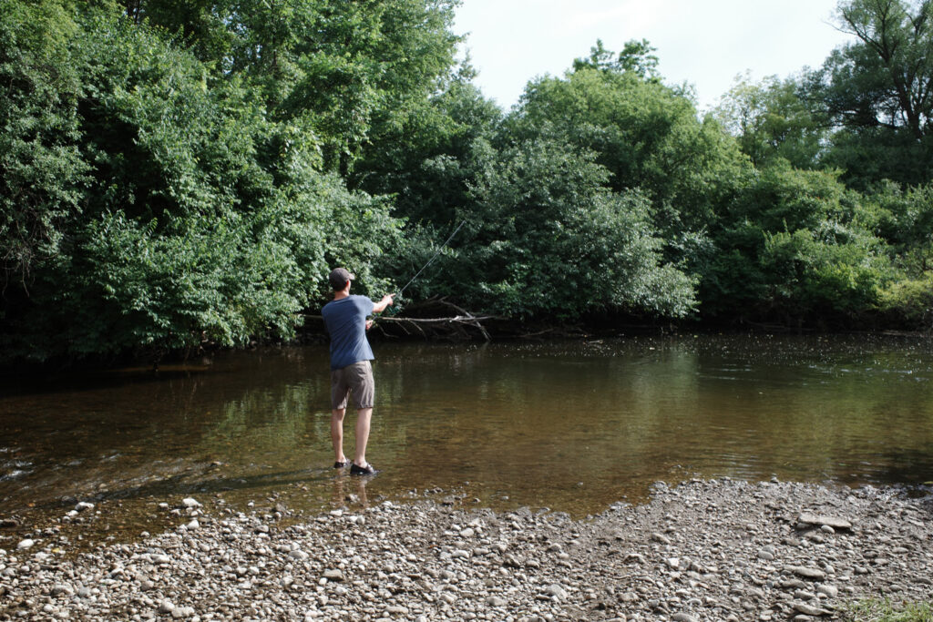 Man casting fishing reel into river.