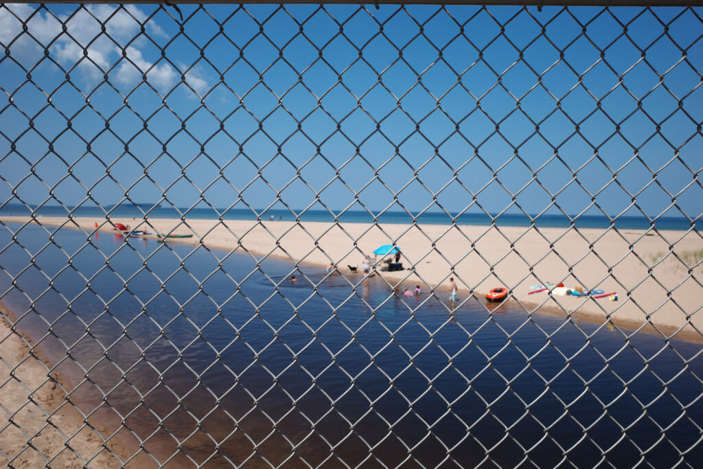 View of river heading out to lake through chainlink fence.