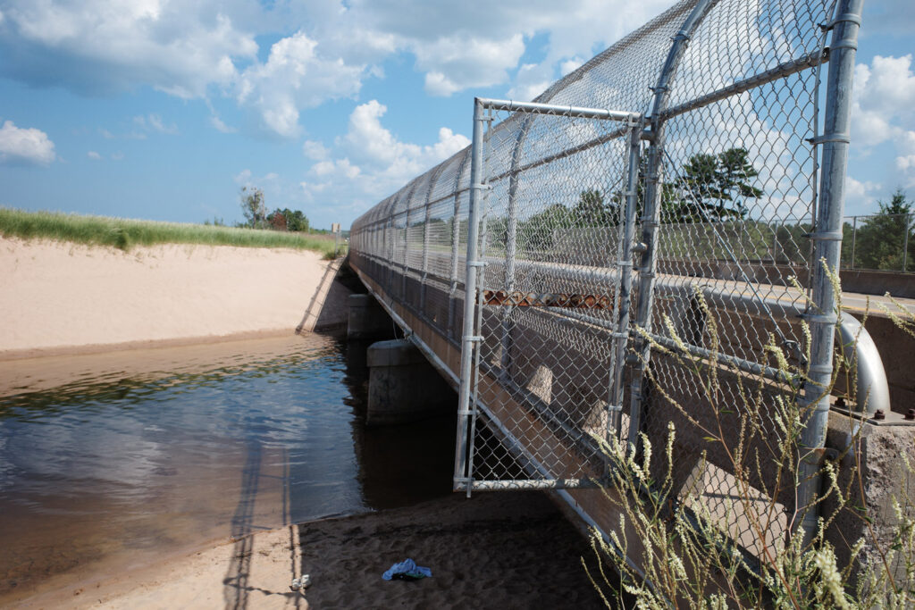 Small bridge over river with chainlink fence over sides.