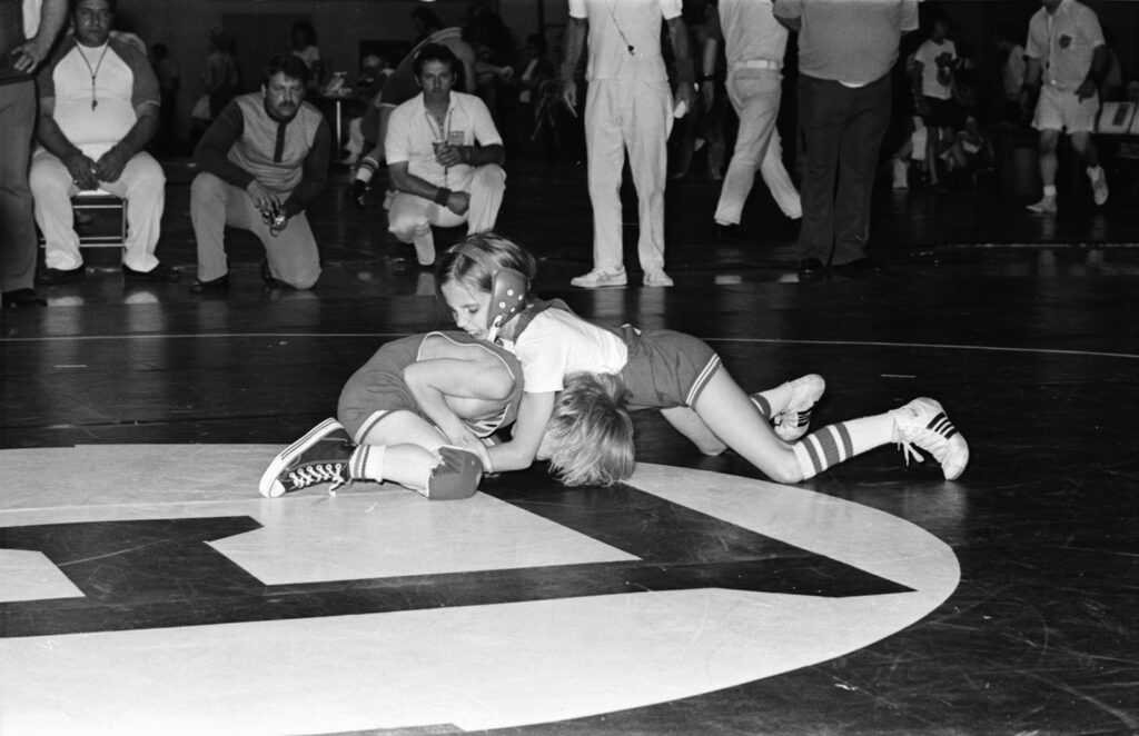 Tricia as a young girl pinning a boy to the mat during a match.