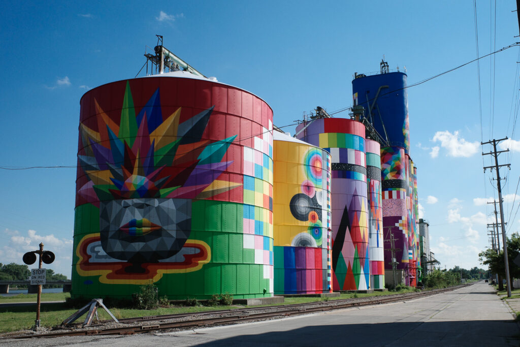 Colorful mural with blocky figures painted on grain silos.