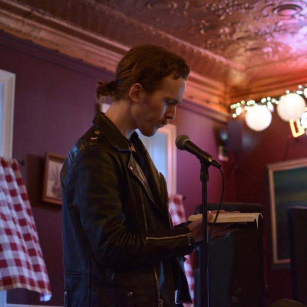 Man speaking into microphone with book at event.