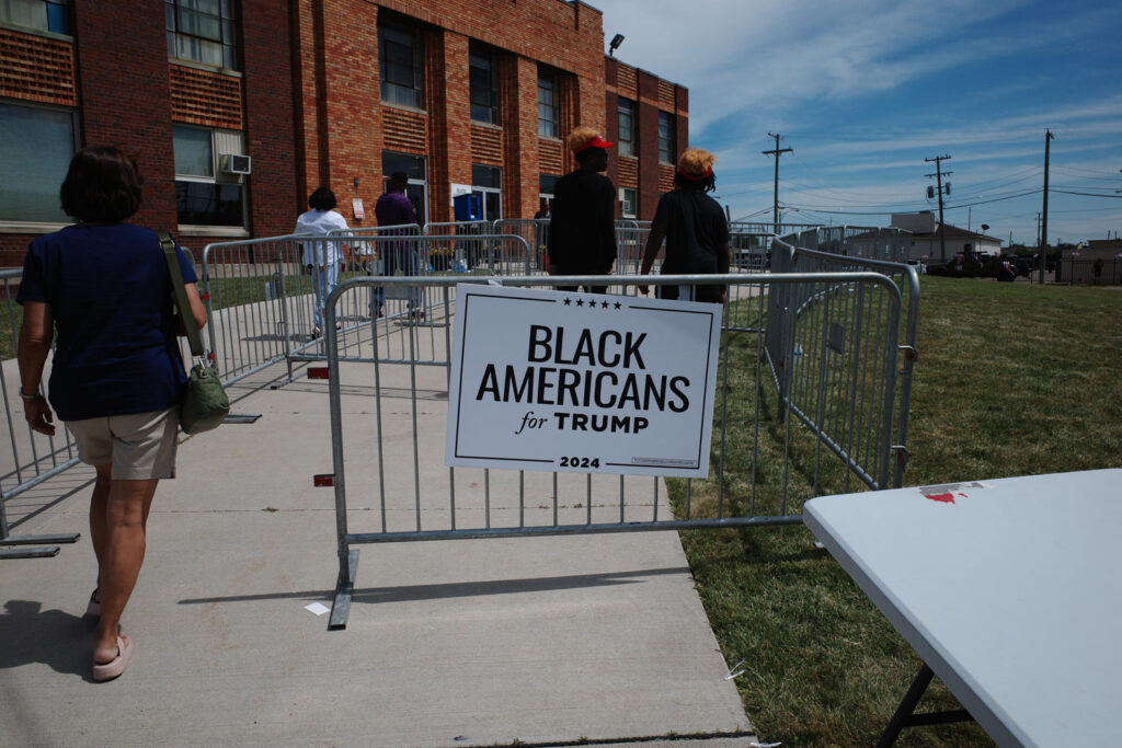 Black Americans for Trump 2024 sign outside Trump event with people entering.