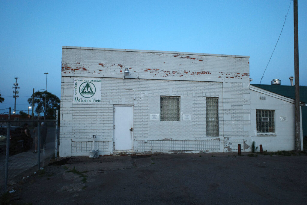 White brick building with sign in spanish reading "Alcoholicos Anonomos grupo volver a vivir"