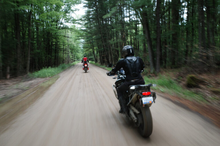 Two men on motorcycles riding on trail.