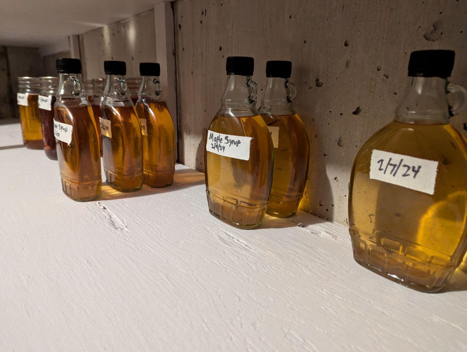 Jars of homemade maple syrup labeled with dates.