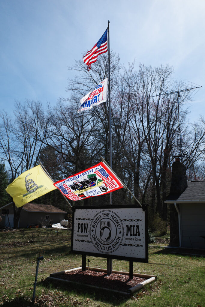 Roadside flag display with Trump, Gadsden, American, and POW-MIA flags.