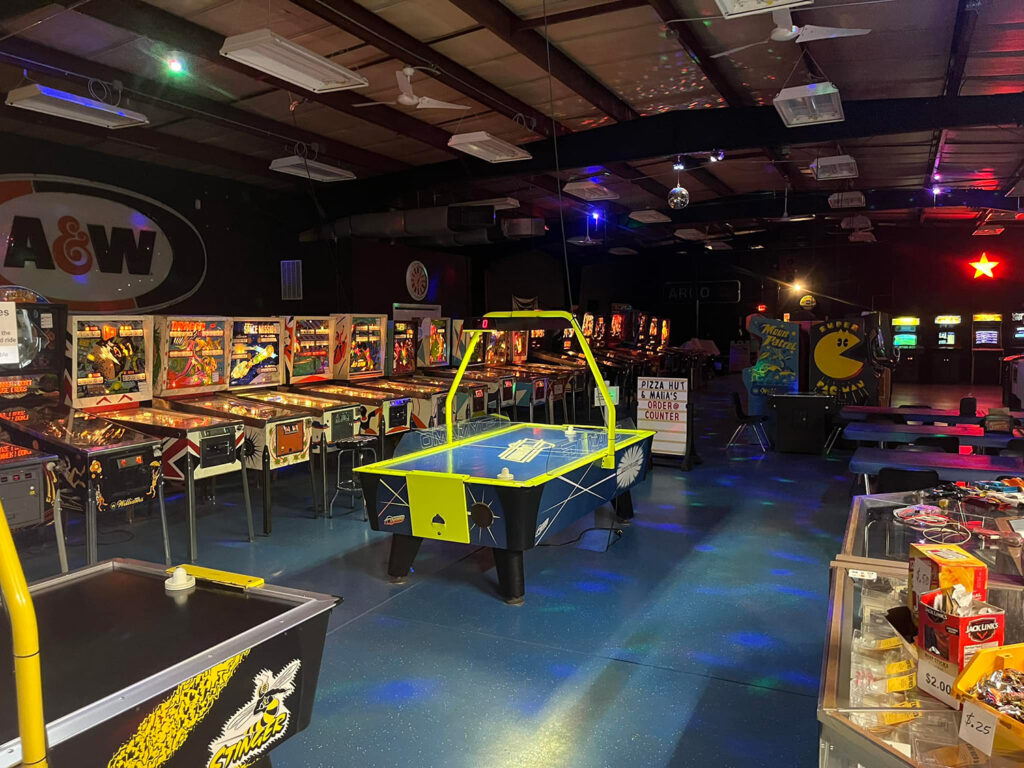 Inside of arcade with games and sign reading "Pizza Hut & Mama's Order @ Counter" and A&W root beer sign