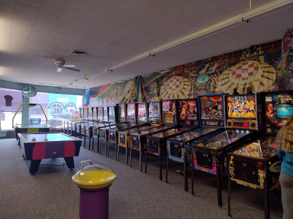 Inside of arcade with pinball tables and air hockey table.