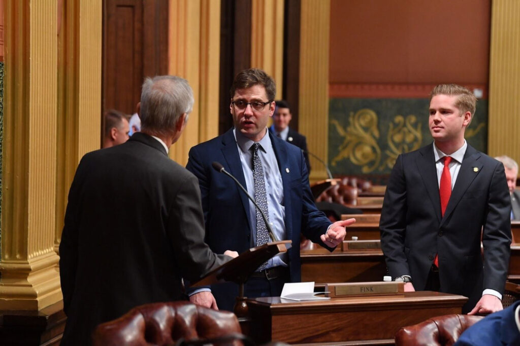 Representative Fink talking with lawmakers in chambers.