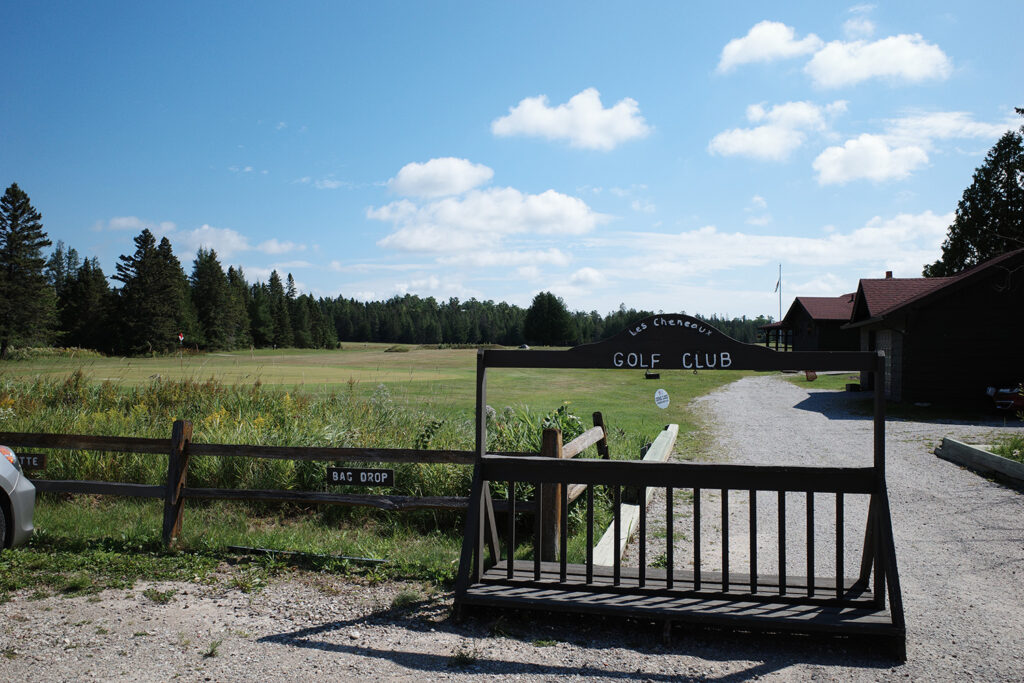 View of golf course with signs saying "Les Cheneux Golf Club" and "Bag Drop"