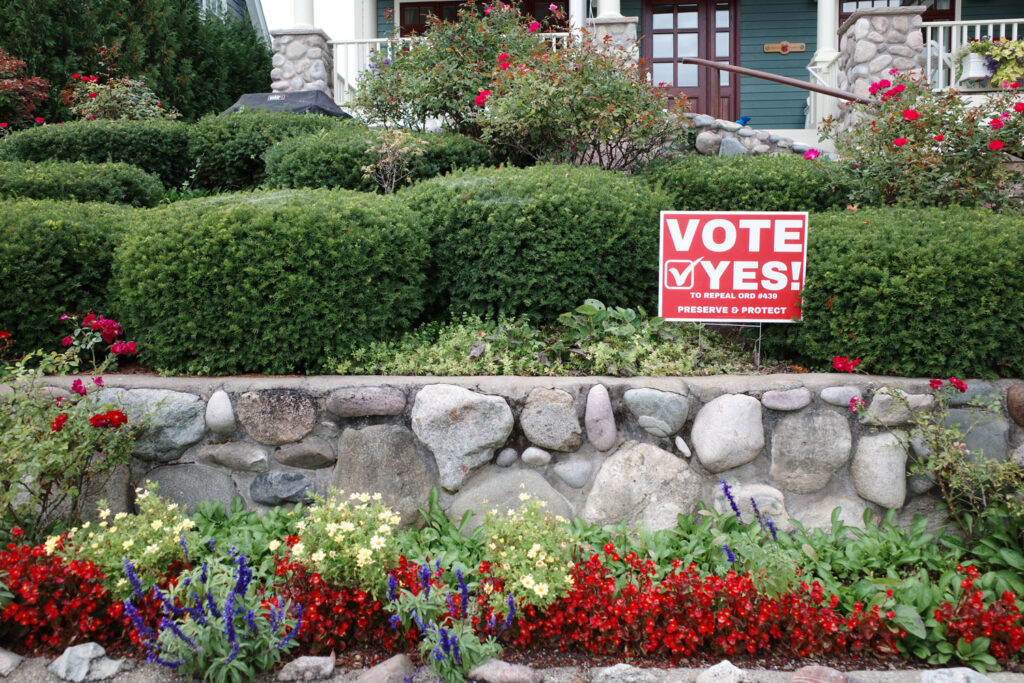 Lawn sign in garden reading "vote yes to repeal ord #439 preserve and protect"