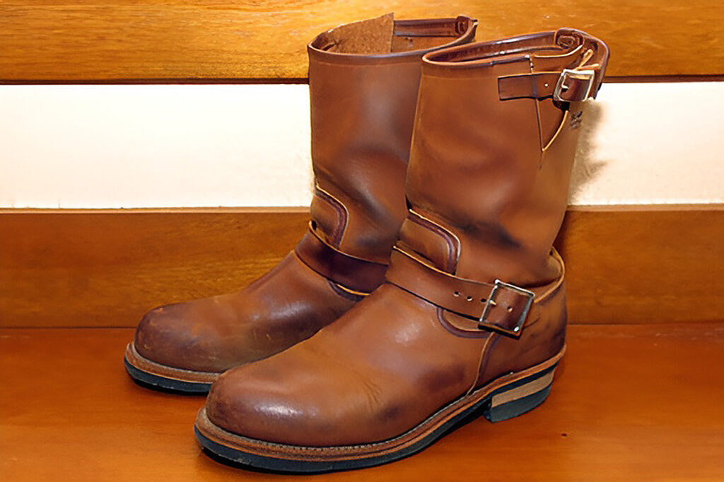 Brown engineer boots on wood paneling.