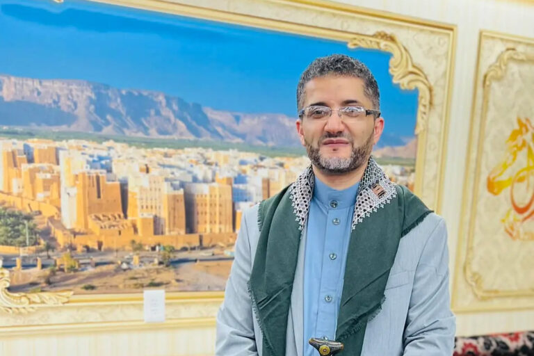 Amer Ghalib posing in front of indoor mural painting.