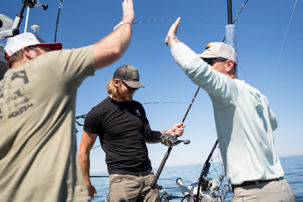 Salmon fishers on boat high fiving.