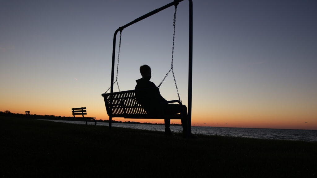 Man on bench swing at sunrise