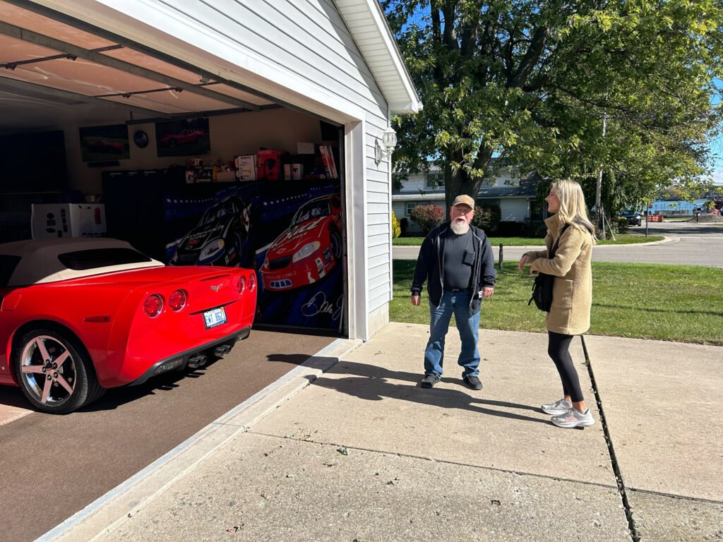 Rylee Linting talking to man outside garage with a red corvette inside