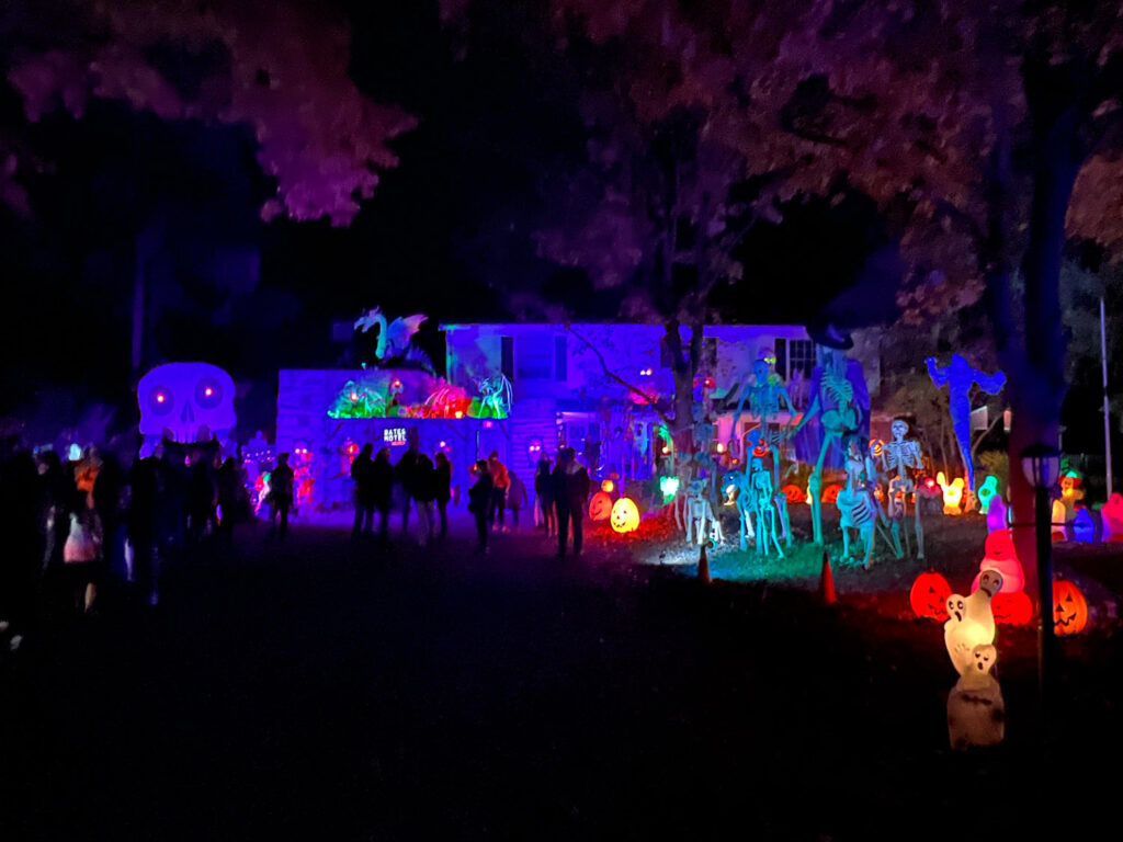 Haunted house lit up at night with crowd outside