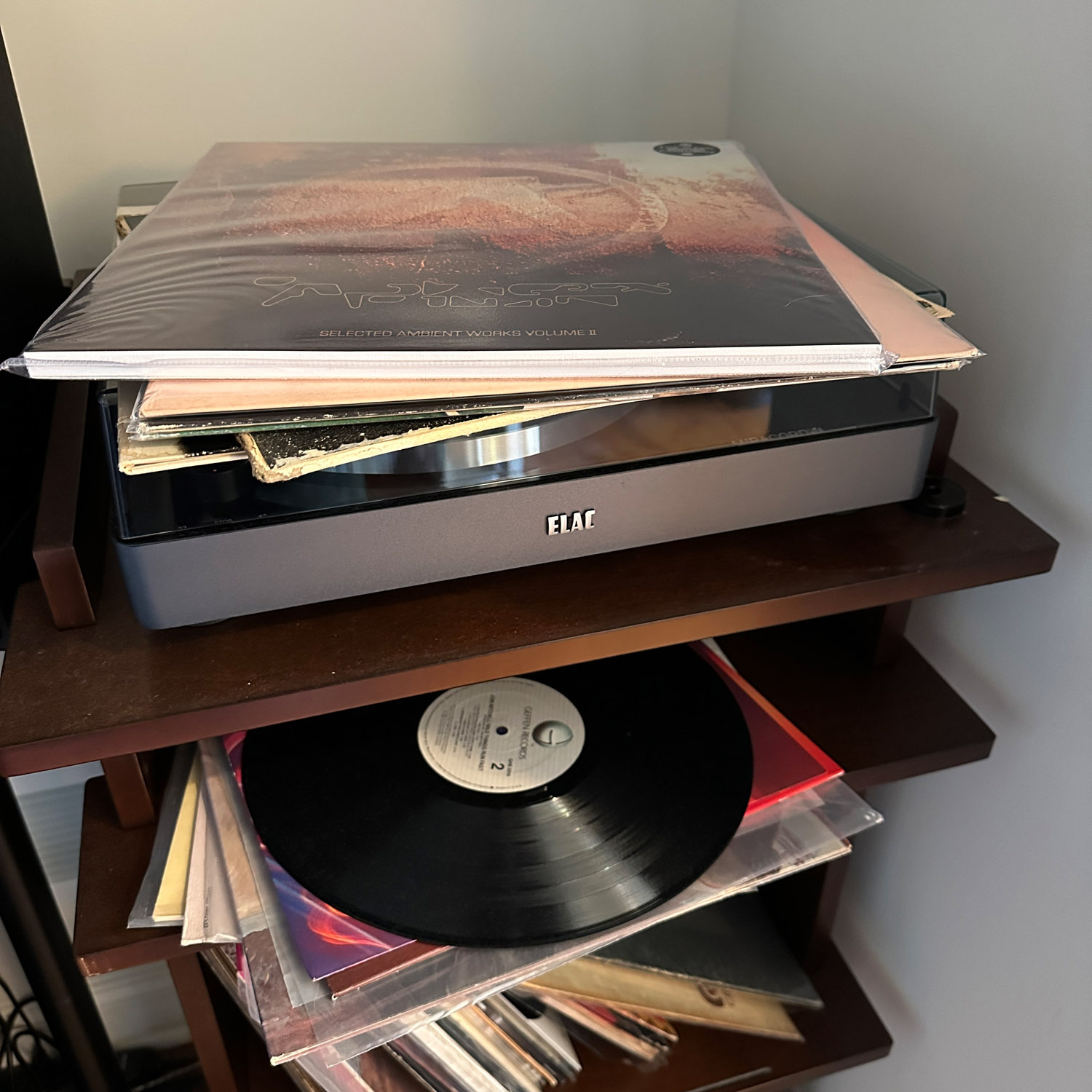 Stack of vinyl records on stand next with turntable.